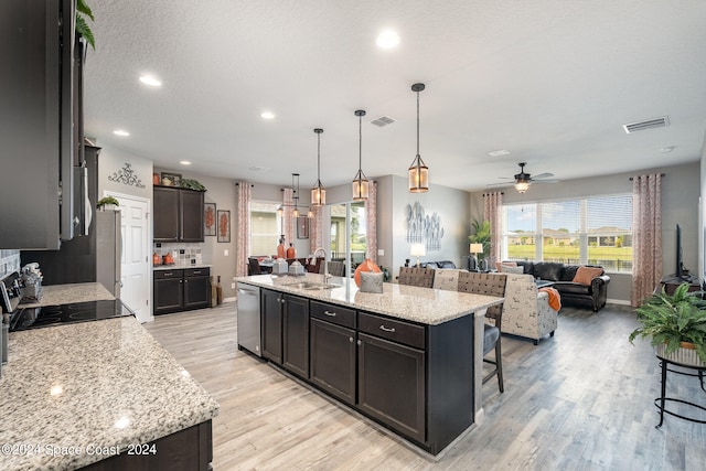 kitchen with a breakfast bar, pendant lighting, dishwasher, a kitchen island with sink, and sink