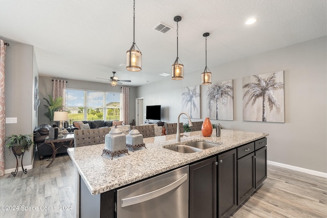 kitchen with light hardwood / wood-style floors, dishwasher, pendant lighting, a kitchen island with sink, and sink