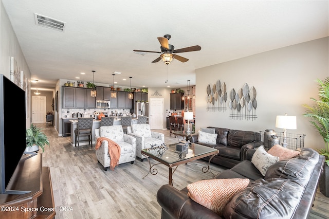 living room with light hardwood / wood-style flooring and ceiling fan