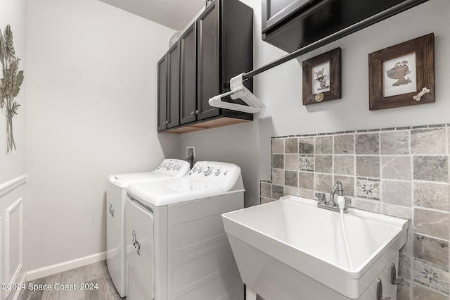 washroom with sink, a textured ceiling, cabinets, separate washer and dryer, and light hardwood / wood-style floors