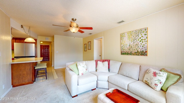 carpeted living room with a textured ceiling and ceiling fan