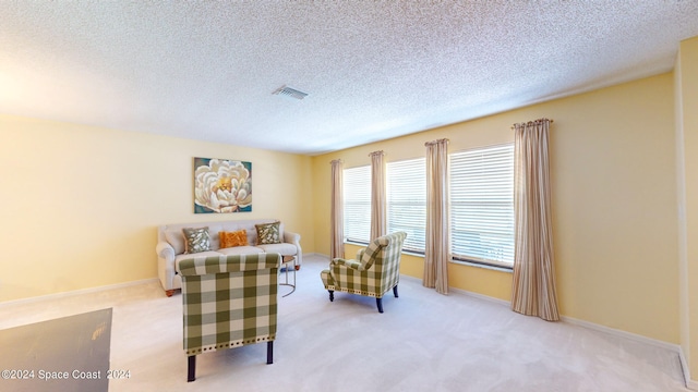 living area with a textured ceiling and light colored carpet