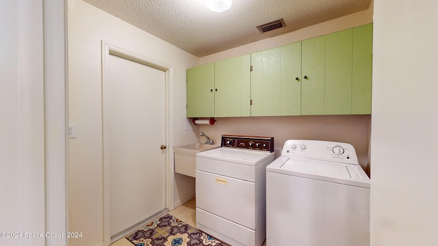 laundry area featuring cabinets, a textured ceiling, washer and dryer, and sink