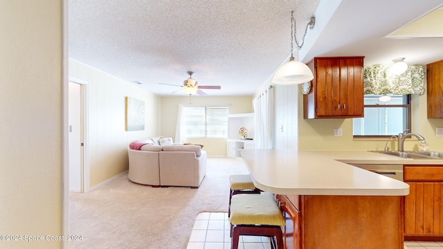 kitchen featuring a breakfast bar, a textured ceiling, light carpet, decorative light fixtures, and ceiling fan