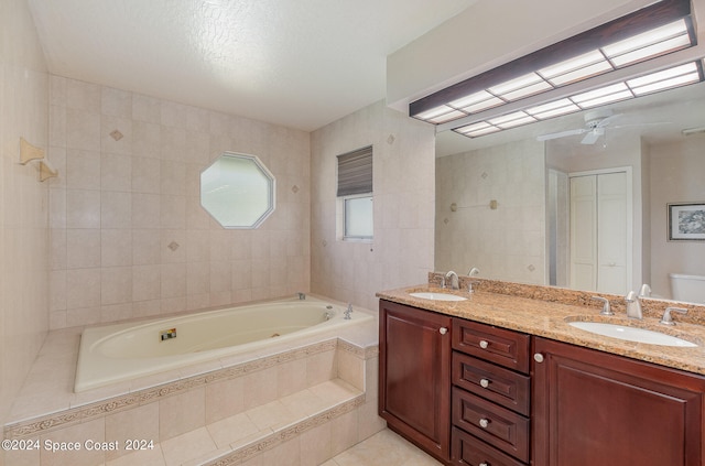 bathroom with ceiling fan, a relaxing tiled tub, vanity, and toilet