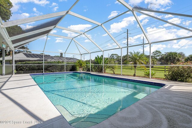 view of swimming pool with glass enclosure and a patio