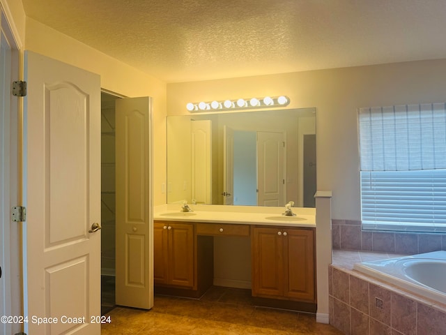 bathroom featuring a relaxing tiled tub, vanity, tile patterned flooring, and a textured ceiling