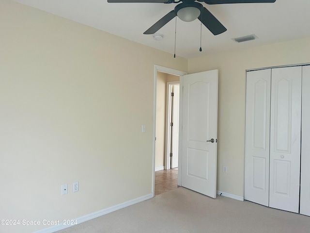 unfurnished bedroom with ceiling fan, light colored carpet, and a closet