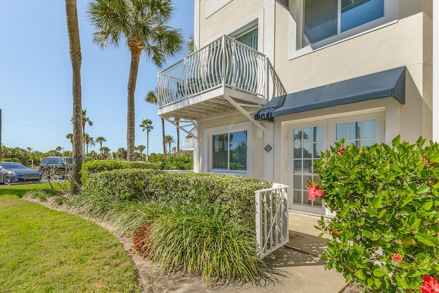 entrance to property with stucco siding and a balcony