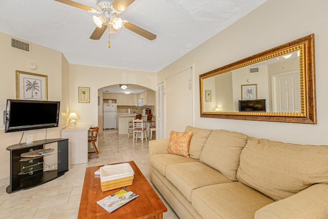 living area featuring arched walkways, a ceiling fan, and visible vents