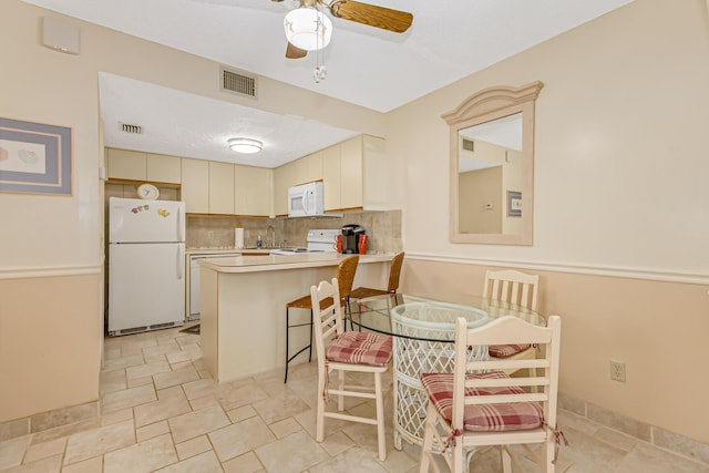 kitchen with ceiling fan, visible vents, light countertops, a peninsula, and white appliances