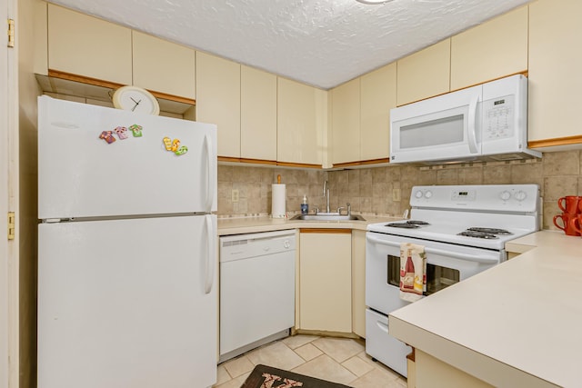 kitchen featuring a sink, cream cabinets, white appliances, and light countertops