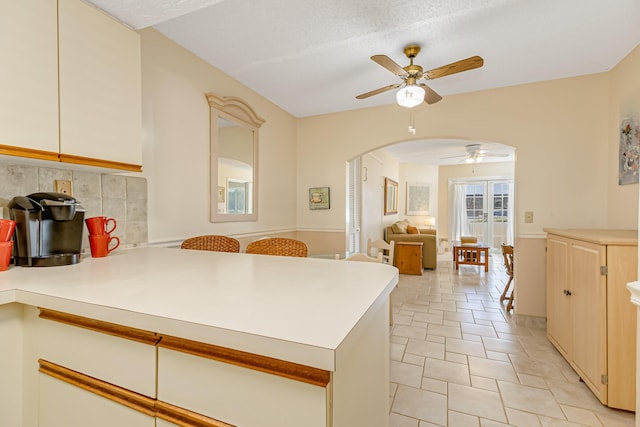 kitchen with ceiling fan, decorative backsplash, arched walkways, a peninsula, and open floor plan