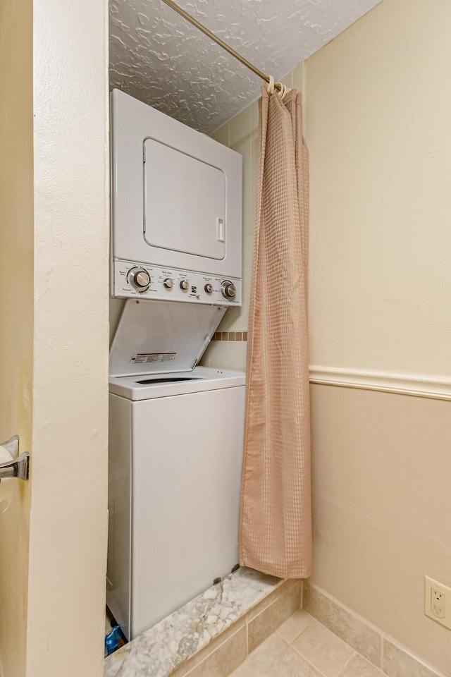 laundry area with laundry area, stacked washer and clothes dryer, and tile patterned floors