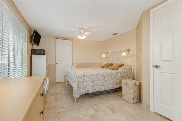 bedroom featuring stone finish flooring, a ceiling fan, and visible vents