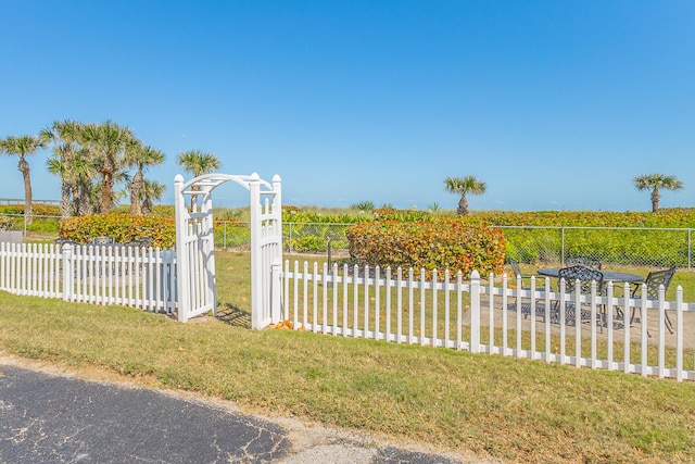 view of gate featuring fence and a lawn