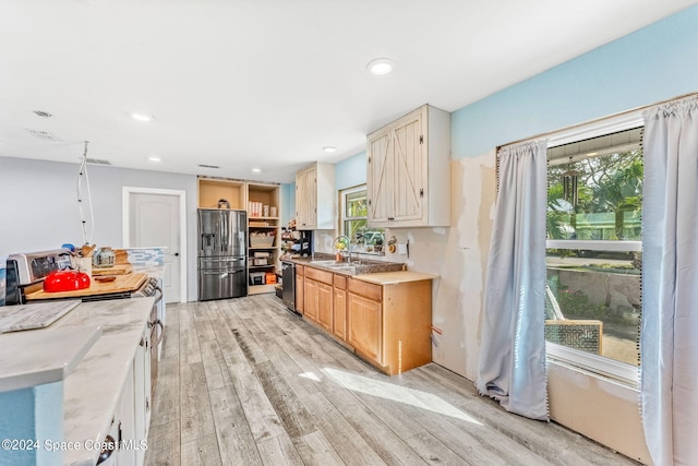 kitchen with light brown cabinetry, appliances with stainless steel finishes, sink, and light wood-type flooring