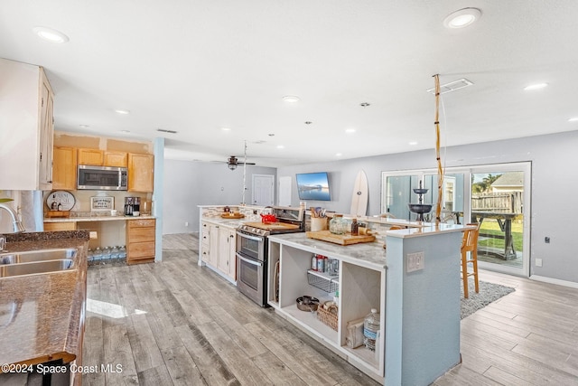 kitchen with light brown cabinetry, appliances with stainless steel finishes, sink, and light wood-type flooring