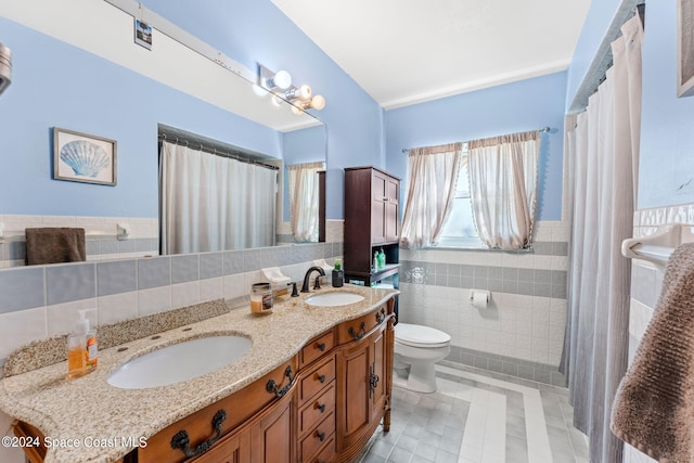 bathroom with toilet, vanity, tile patterned floors, and tile walls