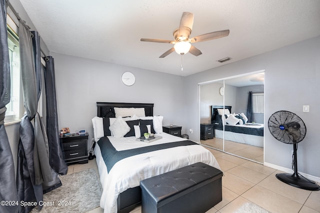 bedroom featuring a textured ceiling, light tile patterned floors, ceiling fan, and a closet