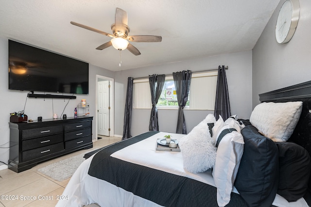 bedroom with ceiling fan, light tile patterned floors, and a textured ceiling