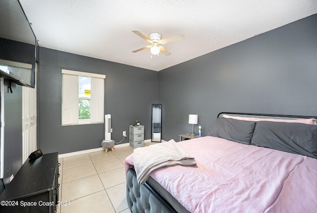 bedroom featuring a textured ceiling, light tile patterned flooring, ceiling fan, and a closet