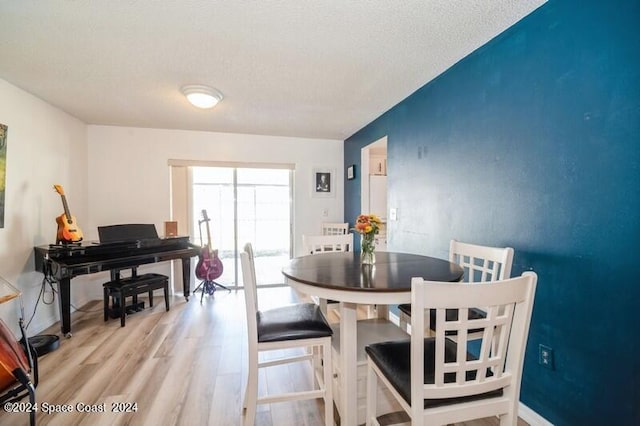 dining space featuring light hardwood / wood-style flooring and a textured ceiling