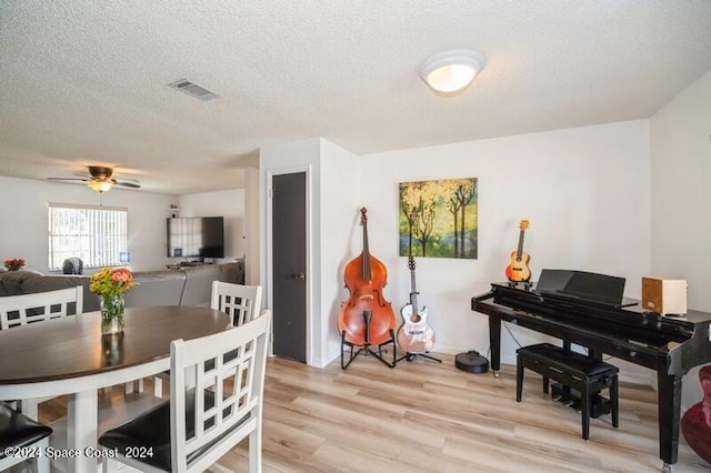 interior space with a textured ceiling, ceiling fan, and light hardwood / wood-style flooring