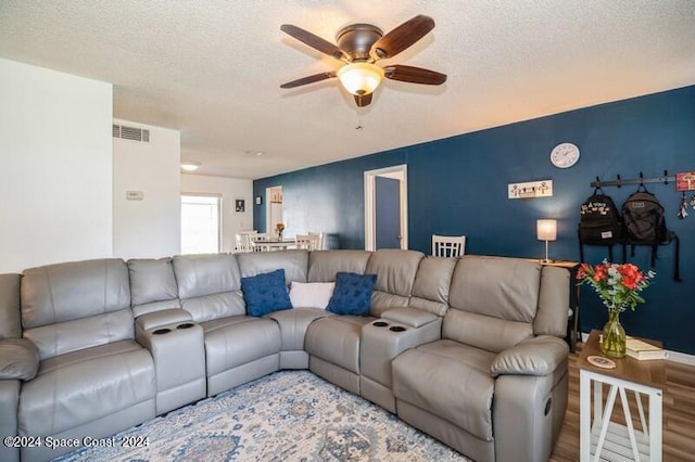 living room with ceiling fan, a textured ceiling, and hardwood / wood-style floors