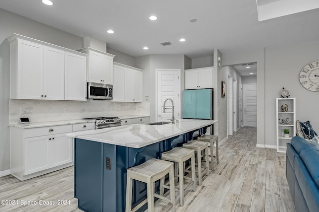 kitchen with light hardwood / wood-style flooring, a kitchen island with sink, stainless steel appliances, and white cabinetry