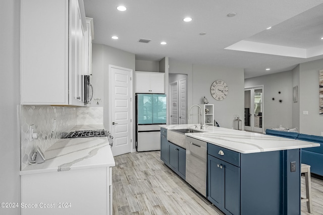 kitchen with blue cabinets, white cabinets, stainless steel appliances, a spacious island, and light hardwood / wood-style floors