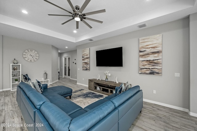 living room featuring a raised ceiling, hardwood / wood-style floors, and ceiling fan