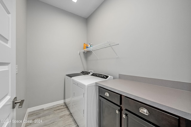 washroom with cabinets, light hardwood / wood-style floors, and washing machine and clothes dryer