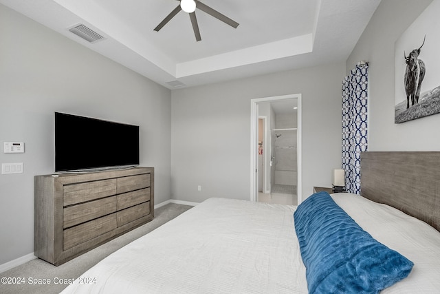 bedroom featuring carpet floors, connected bathroom, a tray ceiling, and ceiling fan