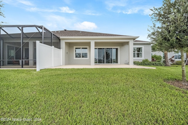 back of house with a lanai, a patio area, and a yard