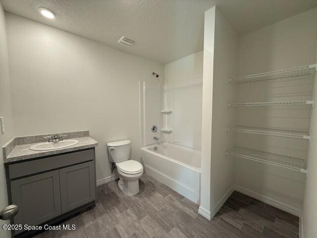 full bathroom with washtub / shower combination, toilet, wood-type flooring, a textured ceiling, and vanity