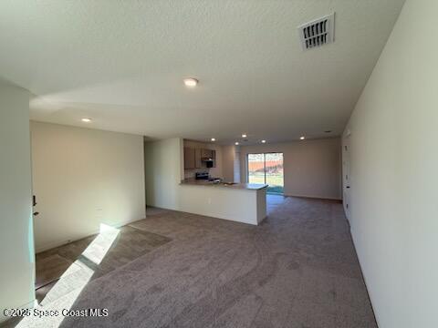 unfurnished living room featuring carpet and a textured ceiling