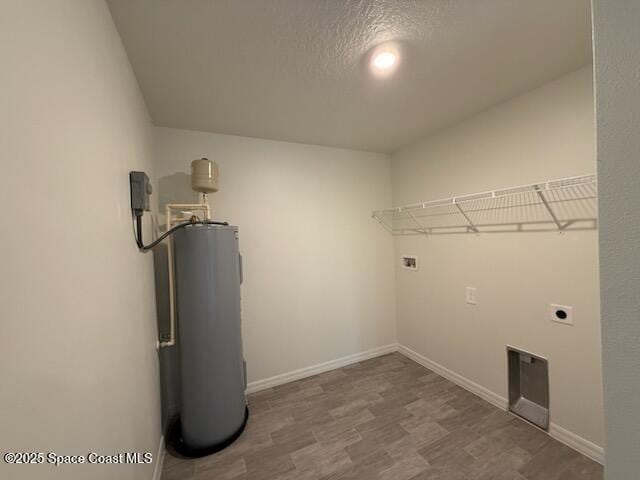 clothes washing area featuring water heater, hardwood / wood-style flooring, hookup for a washing machine, hookup for an electric dryer, and a textured ceiling