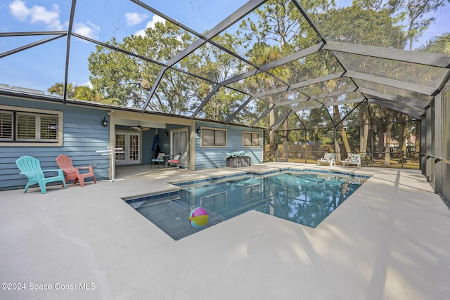 view of pool with glass enclosure, a patio area, french doors, and ceiling fan