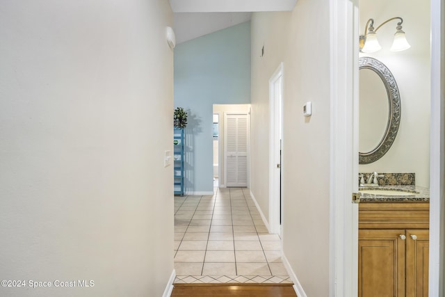 hall with light tile patterned floors, high vaulted ceiling, and sink