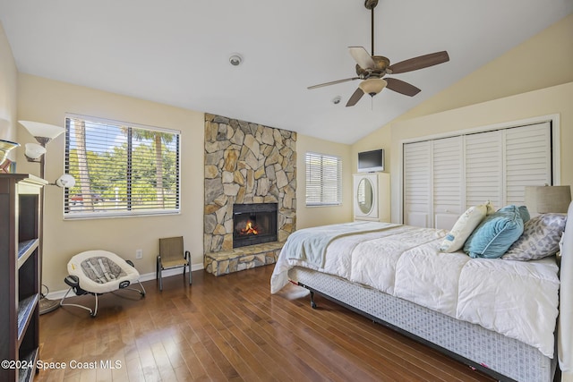 bedroom with lofted ceiling, dark hardwood / wood-style floors, ceiling fan, a fireplace, and a closet