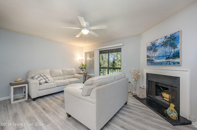 living room featuring ceiling fan, a textured ceiling, and light wood-type flooring