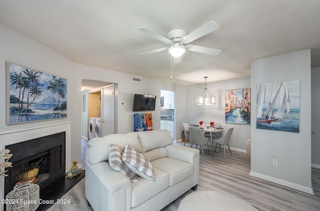 living room featuring light wood-type flooring, independent washer and dryer, a textured ceiling, and ceiling fan