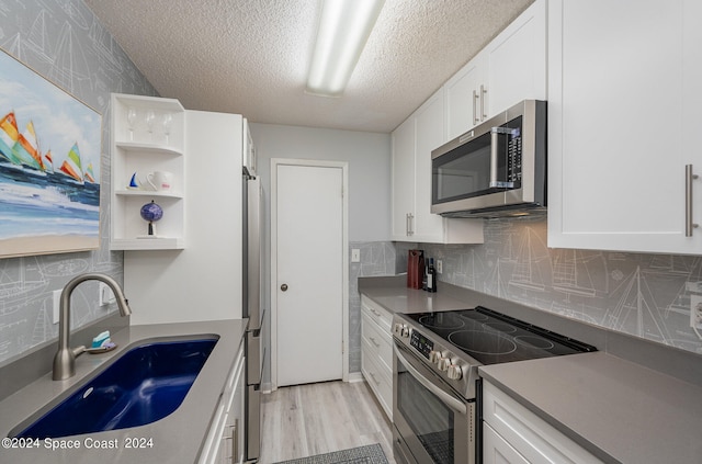 kitchen with light hardwood / wood-style flooring, white cabinetry, appliances with stainless steel finishes, and sink