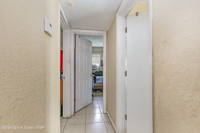 hallway featuring a textured ceiling and light tile patterned flooring