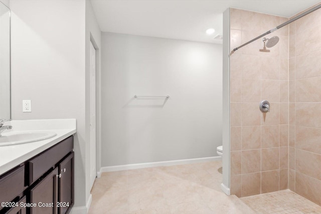 bathroom with tiled shower, vanity, toilet, and tile patterned flooring