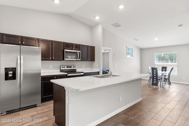 kitchen with light hardwood / wood-style floors, a kitchen island with sink, sink, lofted ceiling, and appliances with stainless steel finishes