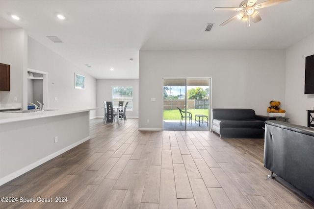 unfurnished living room featuring ceiling fan, light hardwood / wood-style flooring, and sink