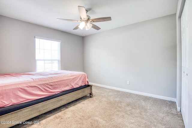 carpeted bedroom featuring ceiling fan and a closet