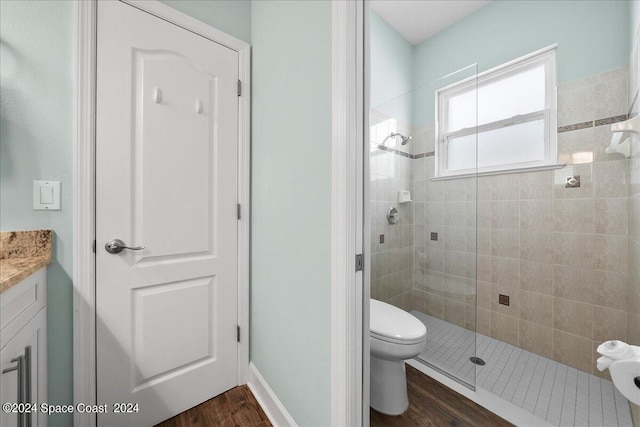 bathroom with vanity, tiled shower, hardwood / wood-style flooring, and toilet